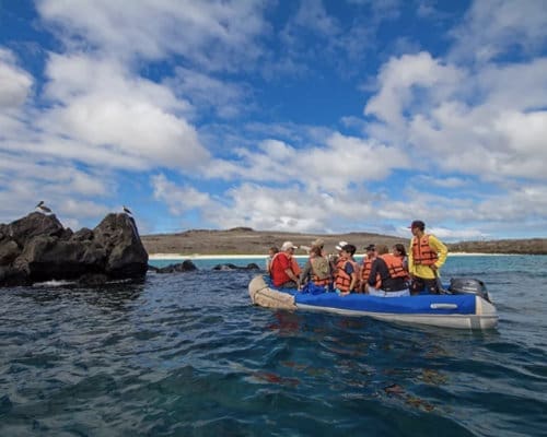 A tour group in a small dinghy makes it way towards a rocky isle